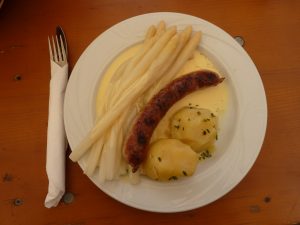 Ein Teller mit Spargel, Kartoffeln und Bratwurst