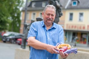 Person zeigt Wurst und Brezel